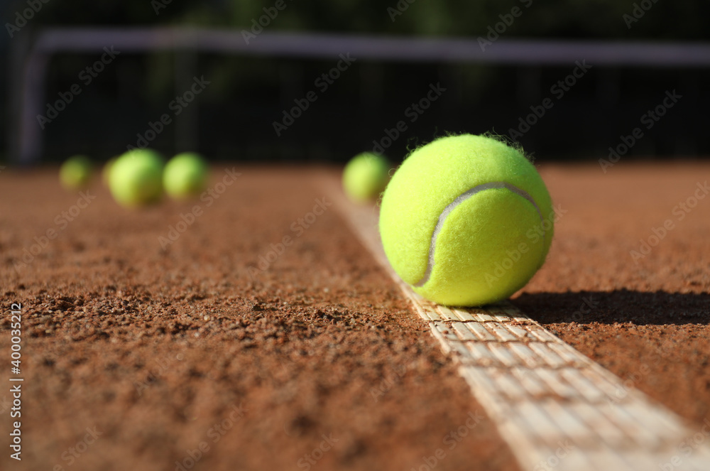 Bright yellow tennis ball on clay court