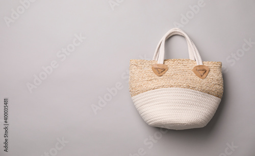 Stylish straw bag on grey background, top view with space for text. Summer accessory