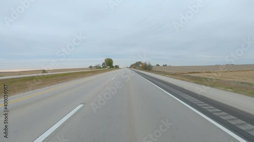 POV driving on a  divided highway empty, harvested fields on a cloudy winter day in rural eastern lowa; flat agricultural landscape photo