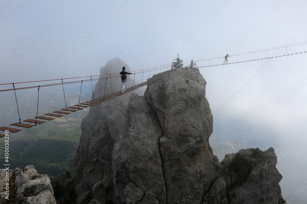 Tourists on a suspension bridge in foggy weather in the Ai-Petri mountains in Crimea Tourists on a suspension bridge in foggy weather in the Ai-Petri mountains in Crimea