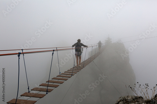 Tourists walk on a suspension bridge in the fog in the Ai-Petri mountains in Crimea