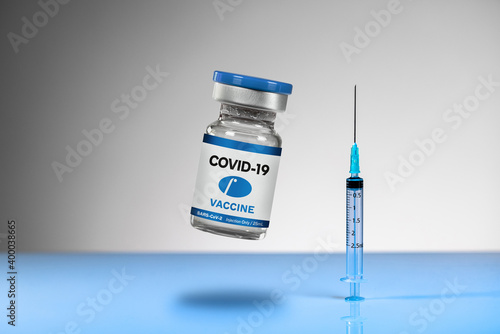Glass ampoule with the inscription COVID-19, vial of a blue VACCINE with syringe, on a blue reflective surface. Intramuscular injections. Possible cure, Solution for Coronavirus pandemic.
