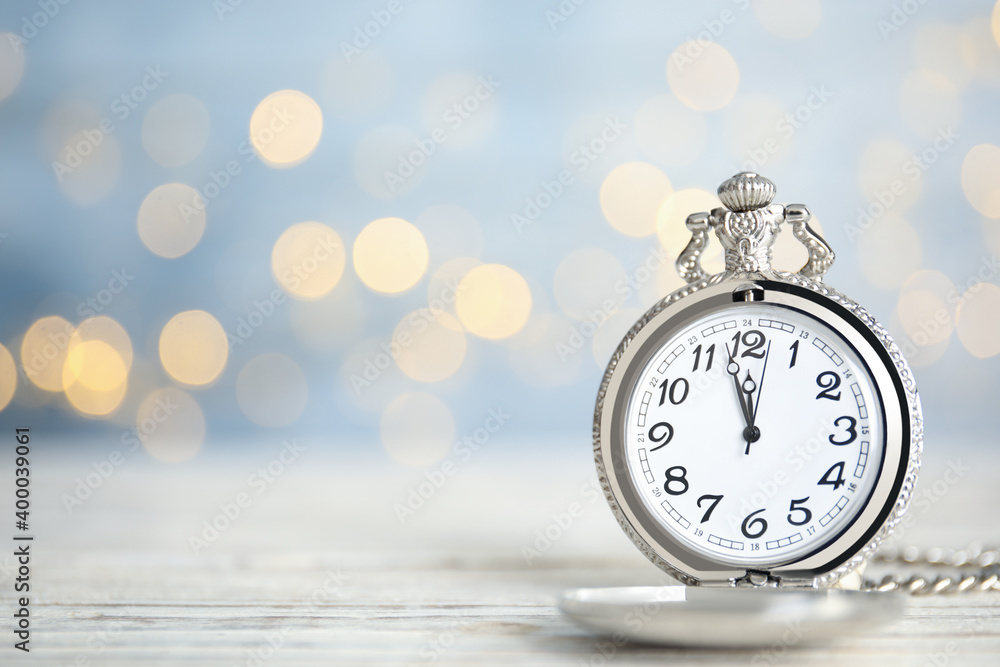 Pocket watch on table against blurred lights, space for text. New Year countdown Pocket watch on table against blurred lights, space for text. New Year countdown