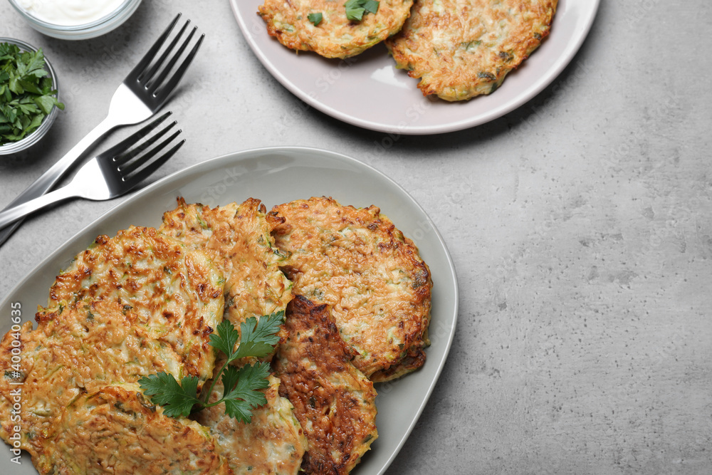Delicious zucchini fritters served on grey table, flat lay Delicious zucchini fritters served on grey table, flat lay