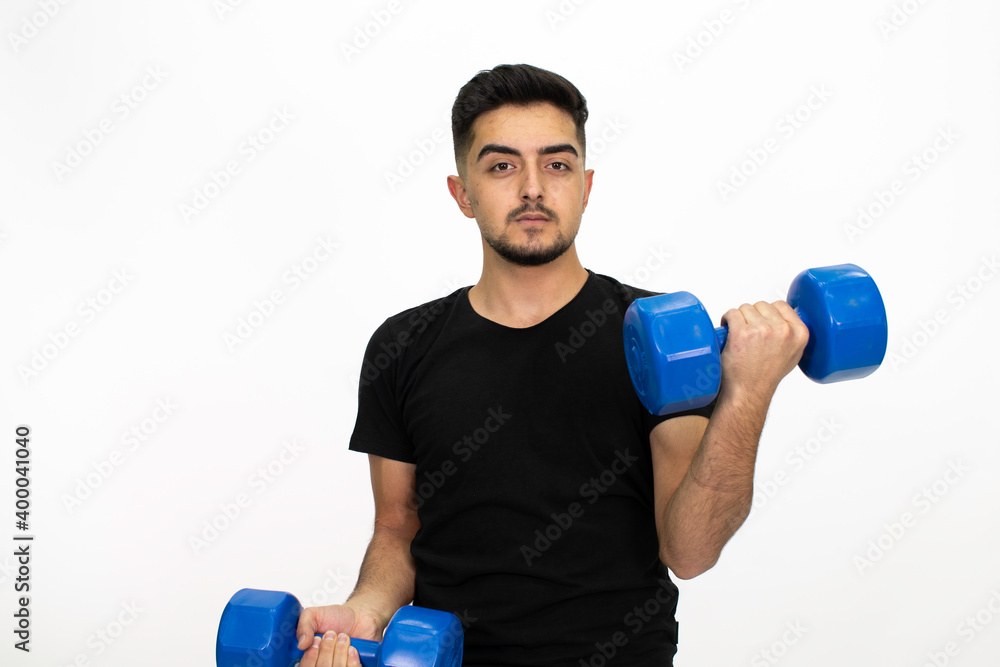Young male model with dumbbells in his hand.Young man doing fitness. He is wearing a black shirt. Isolated pattern and white background.