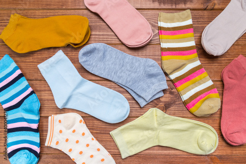multicolored new socks in different sizes stacked on a wooden background. clothes for women