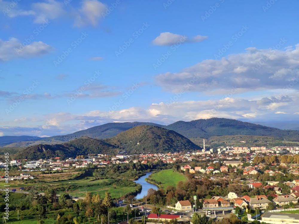 Small european city with small river on low mountains background