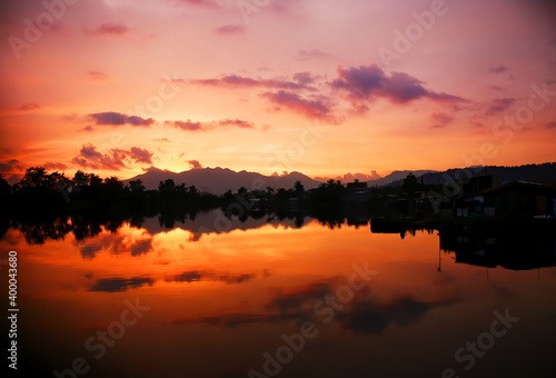 Fiery sunset sky and landscape reflected on water