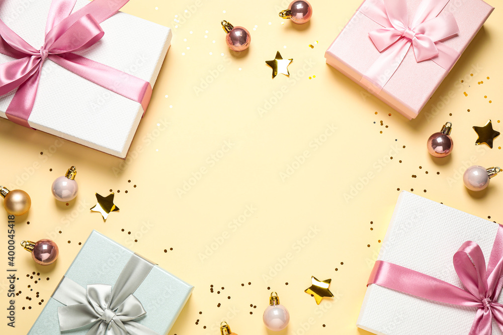 Frame of beautiful gift boxes and Christmas balls on beige background, flat lay. Space for text