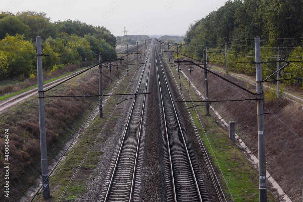 Railway, view from the top. The rails go into the distance beyond the horizon. Two pairs of railways run straight. High quality photo