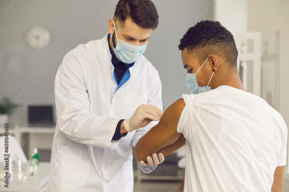 Doctor cleans skin on patient's arm with disinfectant before injecting him with vaccine Doctor cleans skin on patient's arm with disinfectant before injecting him with vaccine