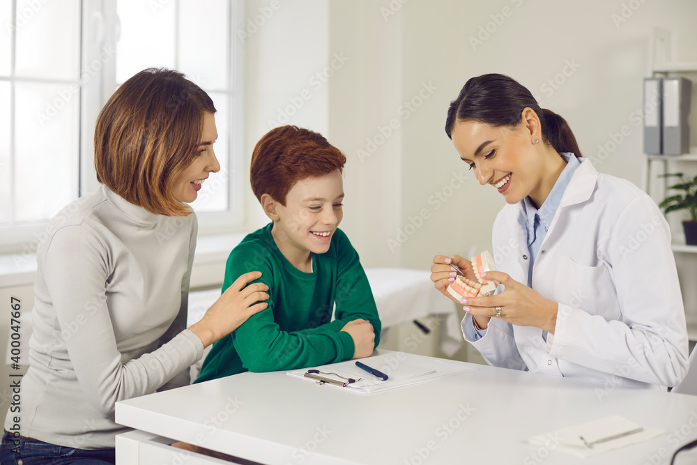Smiling pediatric dentist or oral hygienist teaching patients to brush teeth properly Smiling pediatric dentist or oral hygienist teaching patients to brush teeth properly