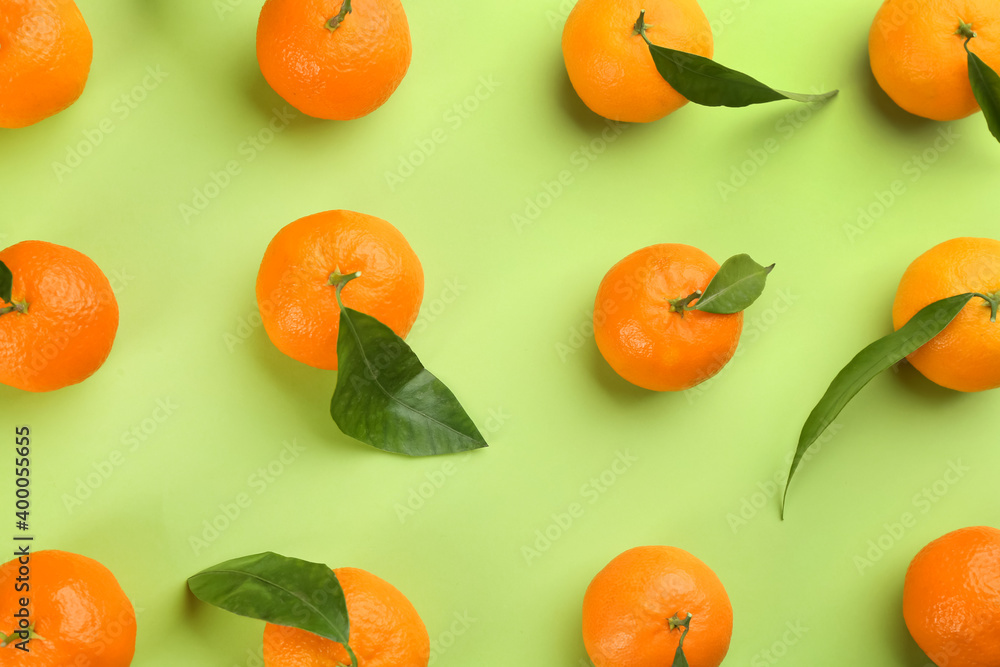 Fresh tangerines with green leaves on light green background, flat lay Fresh tangerines with green leaves on light green background, flat lay