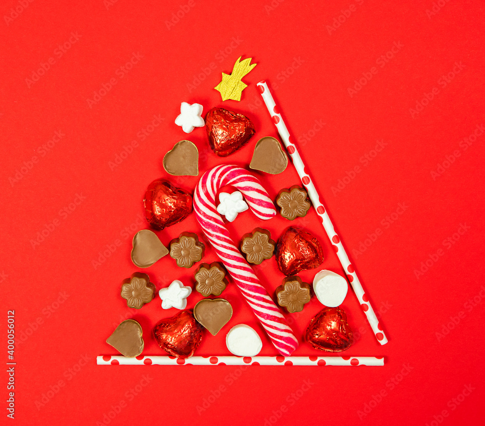 Conceptual Christmas tree made of candies on a red background.