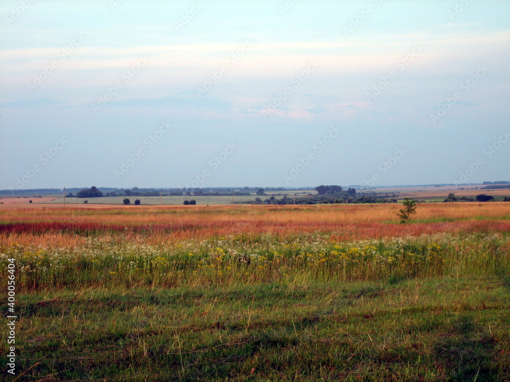 A flat horizon line between the sky and the earth. The sky and clear field in the countryside are illuminated by the rays of the setting sun. A flat horizon line between the sky and the earth. The sky and clear field in the countryside are illuminated by the rays of the setting sun.
