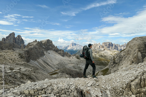 A man hiking in high and desolated mountains in Italian Dolomites. He walks along the mountain rim and enjoys the idyllic landscape. Raw and unspoiled landscape. Sunny day. Endless mountain chains