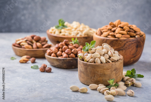 Assortment of nuts in a wooden bowls, on a gray background. Hazelnuts, pistachios, almonds, brazil nut, cashews