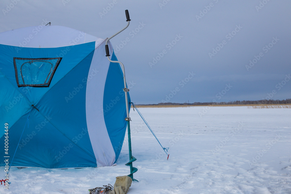 Fototapeta premium blue winter fisherman tent on the background of sunset near the lake