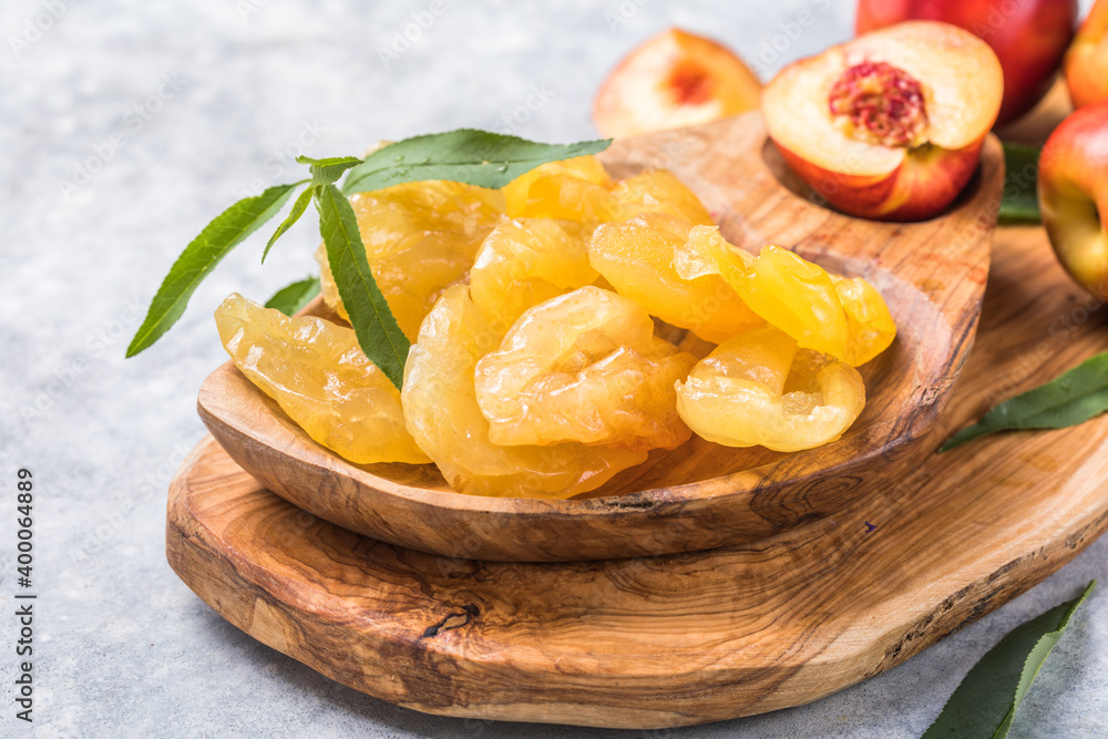 Dried fruits or candied and Fresh peaches with leaves on stone background