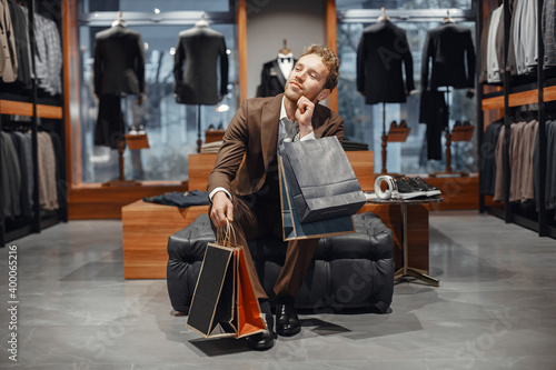 Sale, shopping, fashion, style and people concept. Elegant young man choosing footwear in mall.