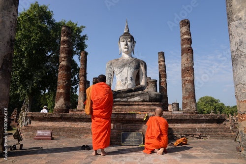 Monks are standing at a Buddha statue in Thailand  Asia.