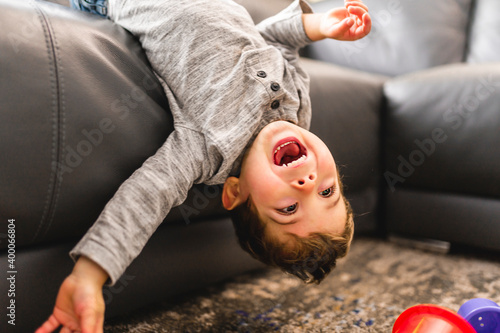 Little boy is standing on sofa at home upside down