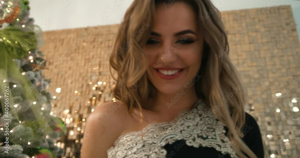 Portrait of a young sexy. Attractive blonde near the Christmas tree and shiny golden background Portrait of a young sexy. Attractive blonde near the Christmas tree and shiny golden background