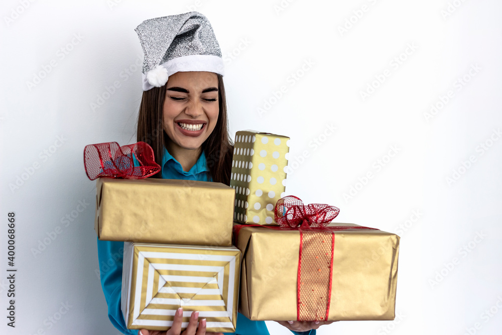 Happy young woman holding a stack of gift boxes. Young woman holding Christmas gifts. Beautiful sexy woman in blue shirt and santa hat with gift box. People, holiday, christmas and celebration concept Happy young woman holding a stack of gift boxes. Young woman holding Christmas gifts. Beautiful sexy woman in blue shirt and santa hat with gift box. People, holiday, christmas and celebration concept