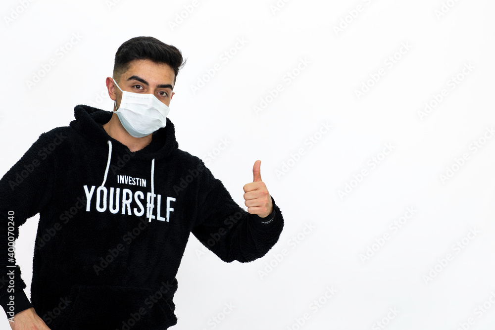 Young man wearing a black hoodie. He's wearing a medical mask. White background. Isolated image.