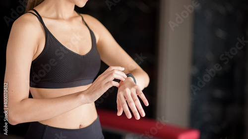 Active woman is using smart watch in fitness gym. Fitness and technology concept .