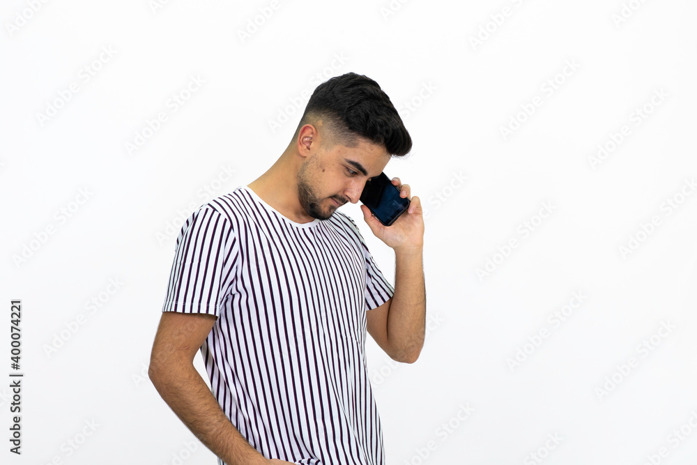 Young man with a phone in hand. Wearing a white striped T-shirt. Got short hidden. White background. Isolated image. Young man with a phone in hand. Wearing a white striped T-shirt. Got short hidden. White background. Isolated image.