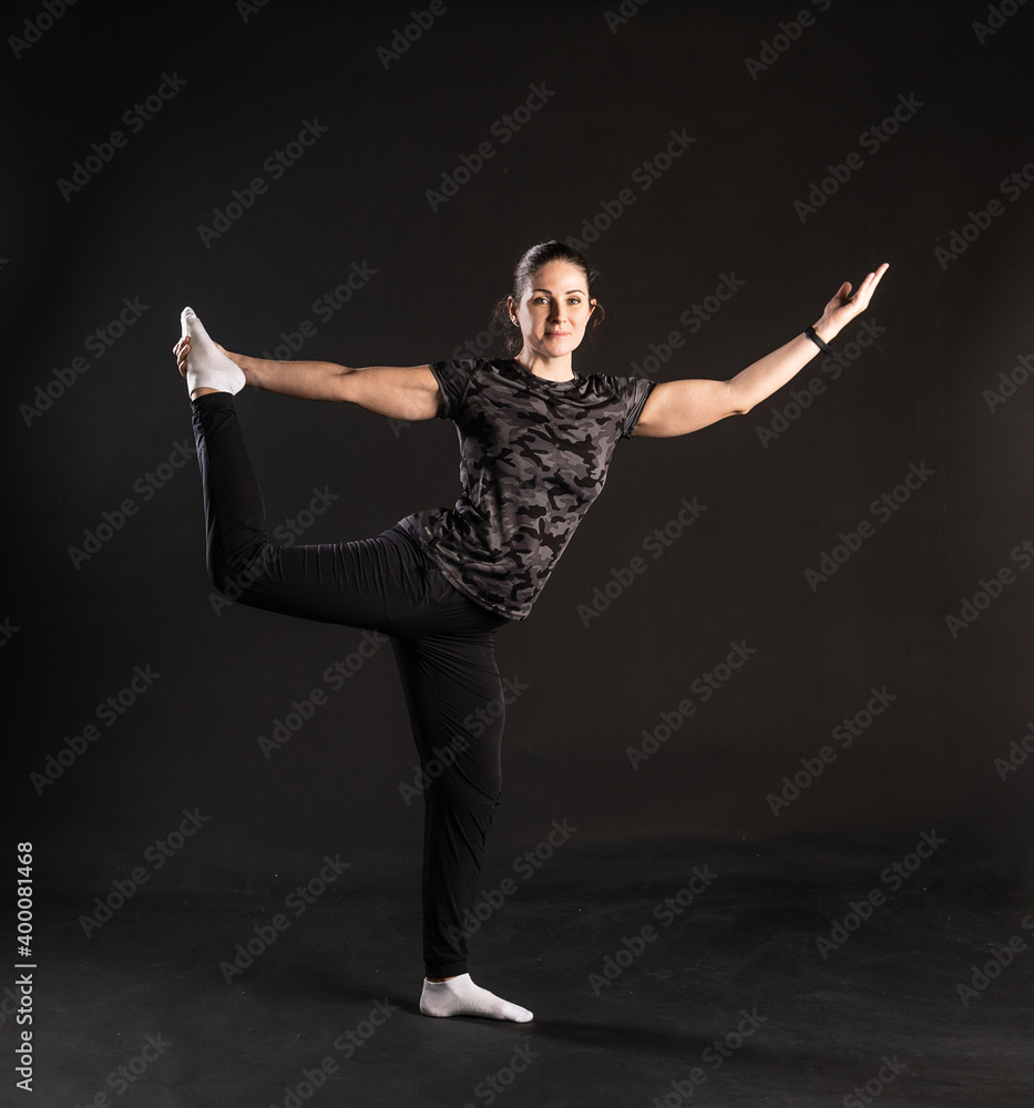 Fitness c Aqua keeps a leg, stands in the rack. Engaged in sports on a black background Happy smiles at the camera Fitness c Aqua keeps a leg, stands in the rack. Engaged in sports on a black background Happy smiles at the camera