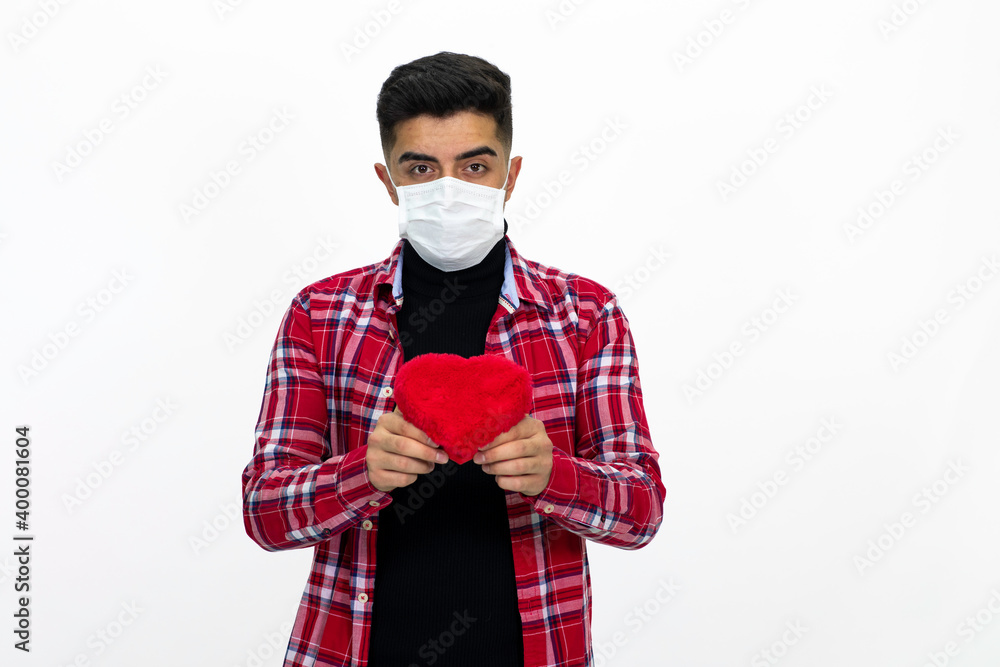 Young man wearing a medical mask, Holding a heart-shaped gift box, wearing a red striped shirt. Young man wearing a medical mask, Holding a heart-shaped gift box, wearing a red striped shirt.
