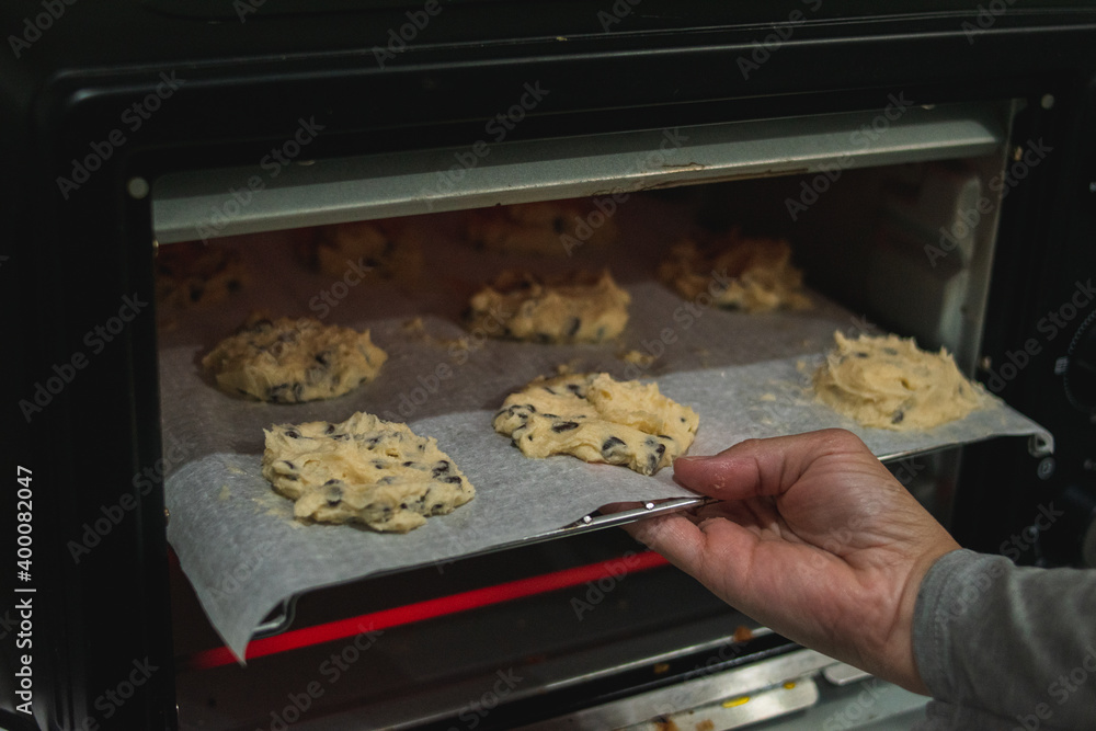 A hand putting a cookie sheet in the oven.