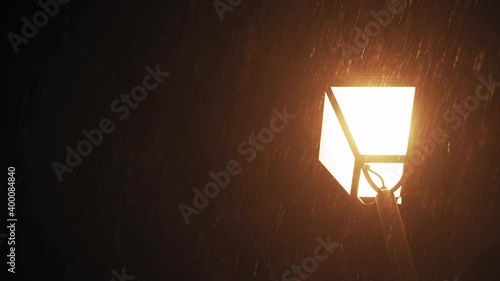 Weather forecast, anomaly, emergency, element, winter concept - panning unstabilized handheld shooting of snowfall. Falling snowflakes in yellow light of street lamps at night park. first snow in kiev photo