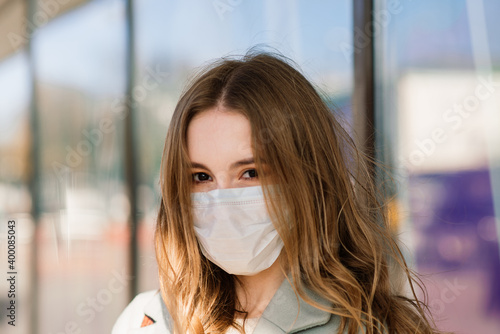 Close up portrait of a caucasian female wearing a medical mask and standing in the street and cafe