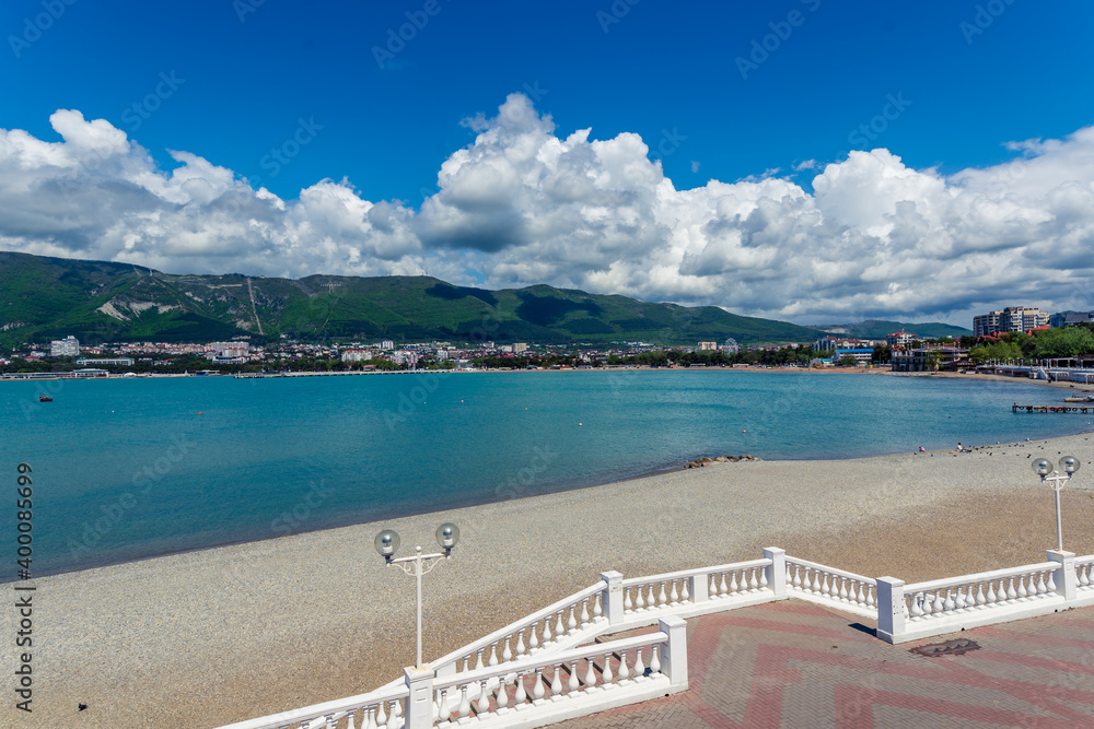 Resort embankment with balustrade and lanterns on the background of the sea and mountains. Beautiful white cumulus clouds. Seaside resort town of Gelendzhik