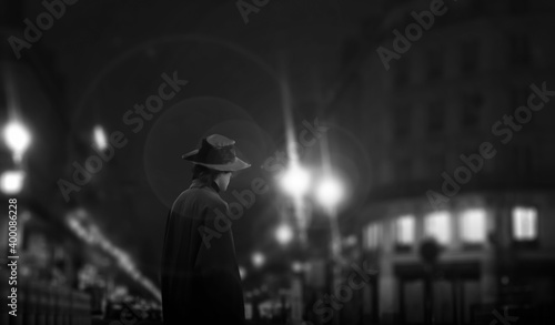 Photography the dark silhouette of a male hat in a night street light.