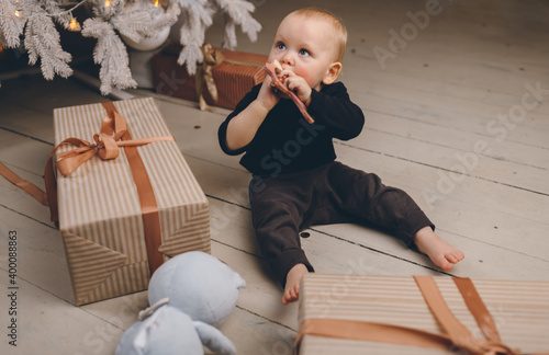 Happy baby boy with presents and toys near Christmas Eve