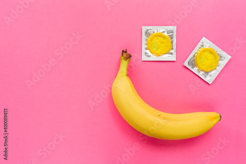Quadro em tela Composition with yellow condoms and banana on pink background