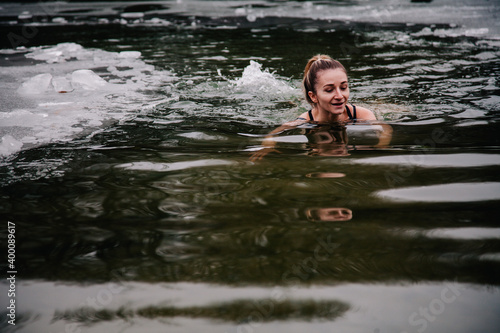 Fototapeta Naklejka Na Ścianę i Meble -  Young slender girl bathes in winter in a river hole