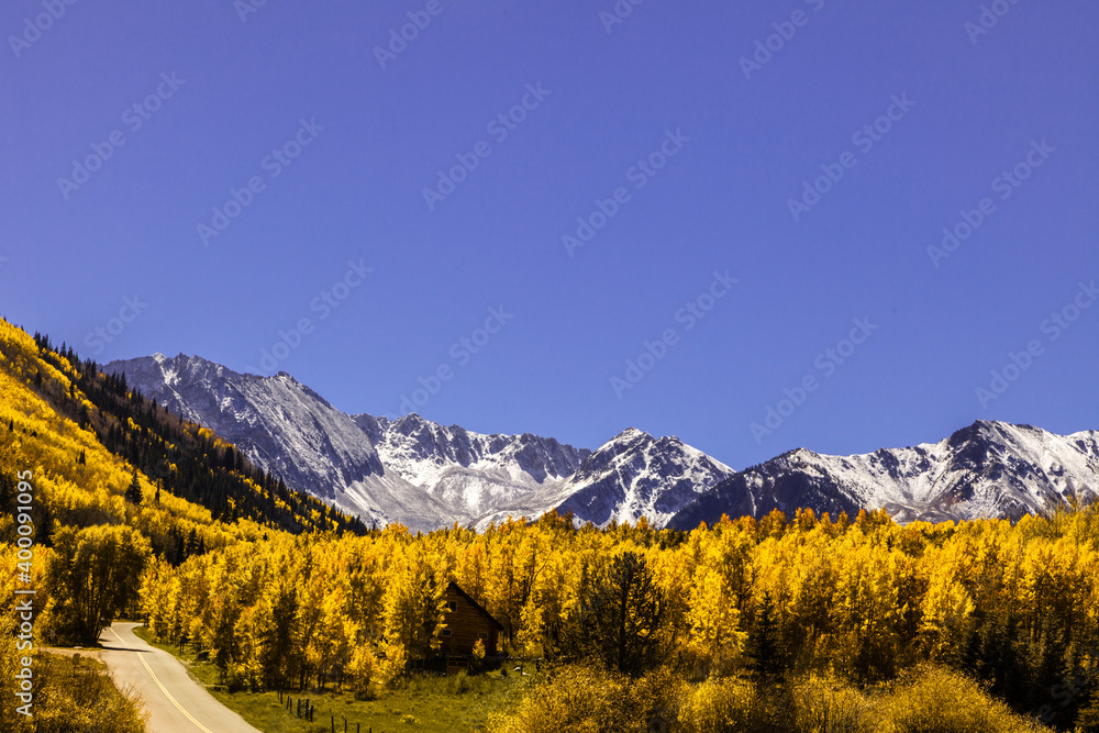 Blue skies over an autumn scene in Colorado with the  snowcapped Rocky Mountains and golden aspens