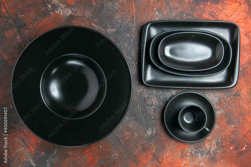 top view black oval and rectangular platters black cup and saucer on dark red background top view black oval and rectangular platters black cup and saucer on dark red background
