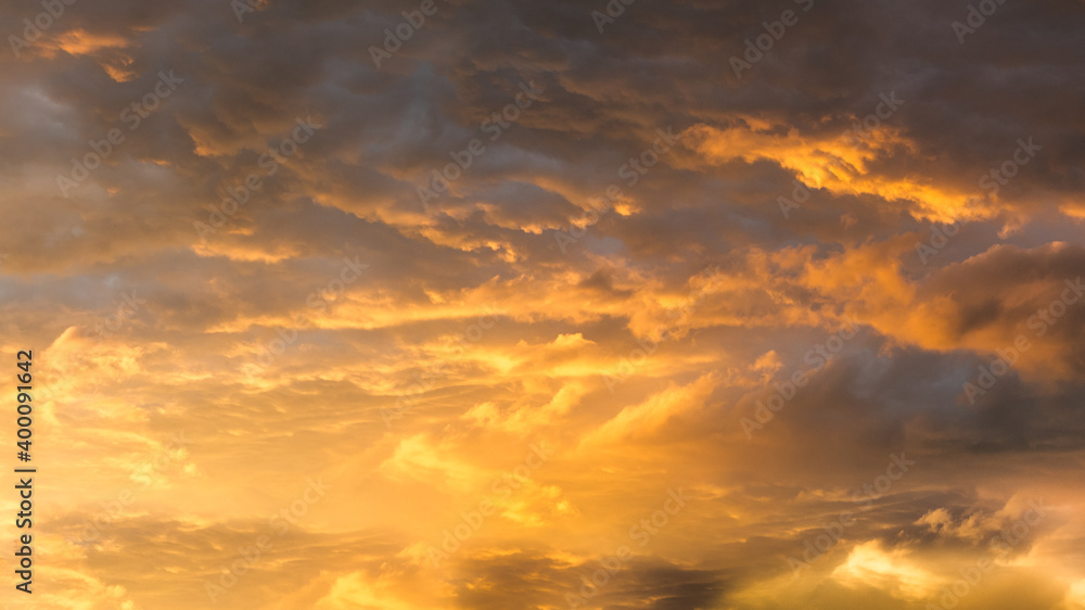 Golden beautiful clouds at sunset background. Bright orange cloudscape and heavenly sky. Faith and freedom concept