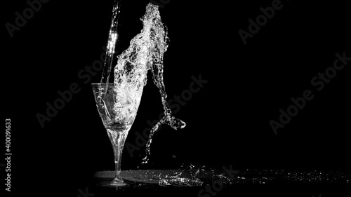 Water splash and wine glass isolated on black background. Pouring fresh water into a wine glass black and white wallpaper. Water spilling out of a crystal cup