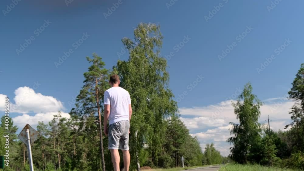Young adult sports man skateboards on the road in the middle of a pine forest Young adult sports man skateboards on the road in the middle of a pine forest