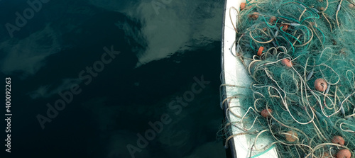 Fishing net in a small fishing boat. Horizontal panoramic crop with large area of dark blue water.