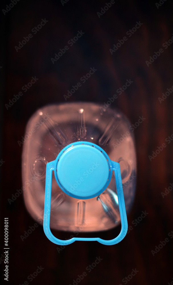 Plastic water bottle in warm light on dark background, selective close view from the top, vertical frame and copy space. Plastic water bottle in warm light on dark background, selective close view from the top, vertical frame and copy space.