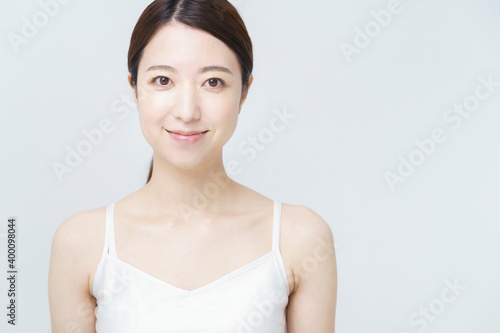 美容・スキンケアイメージ・白いキャミソールを着て微笑む女性