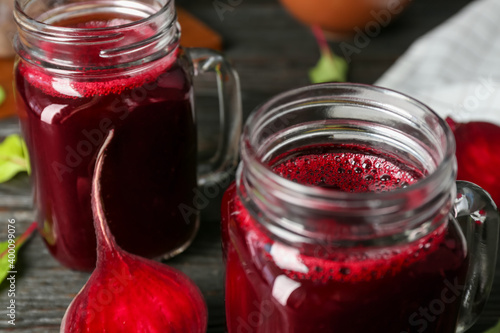 Fresh beet juice and raw vegetable on table, closeup